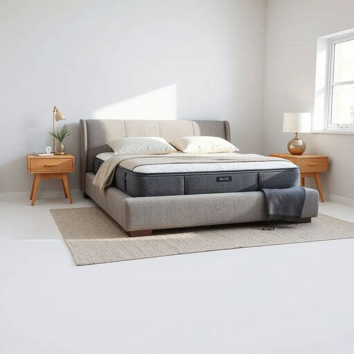 Modern upholstered bed with a neatly styled mattress in a bright, minimal bedroom
